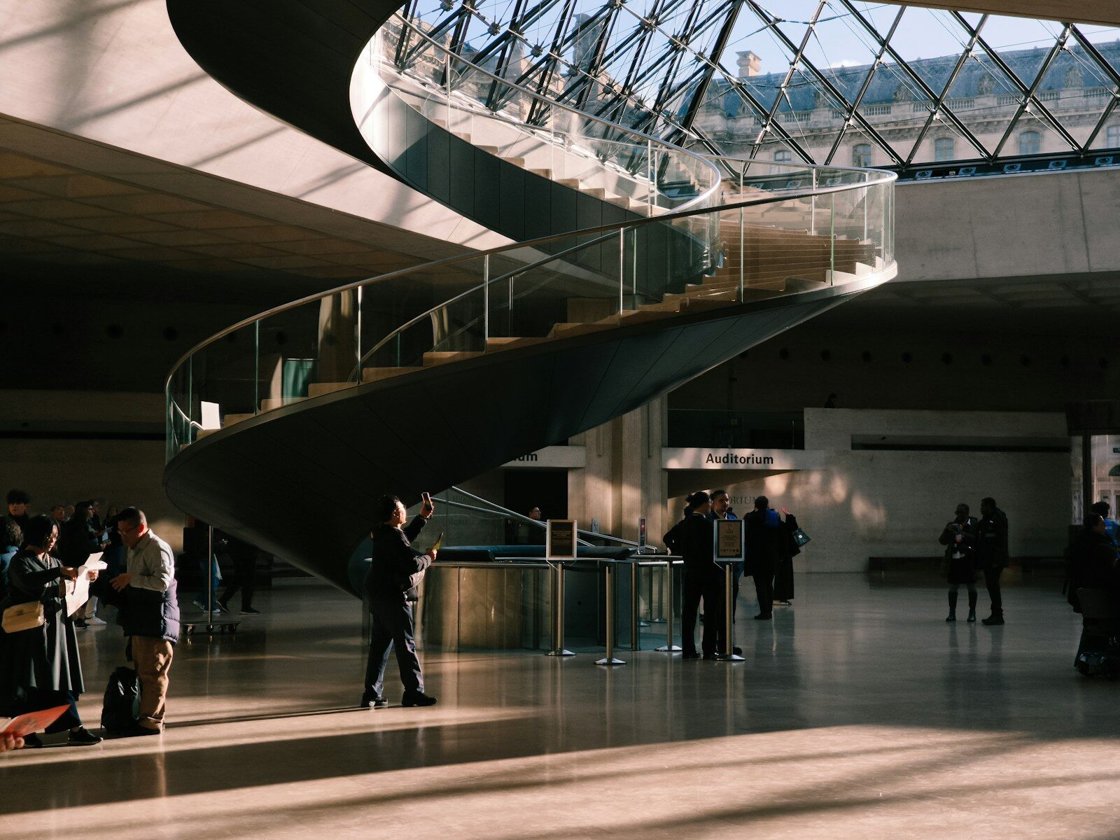 Modern spiral staircase in a sunlit atrium with people